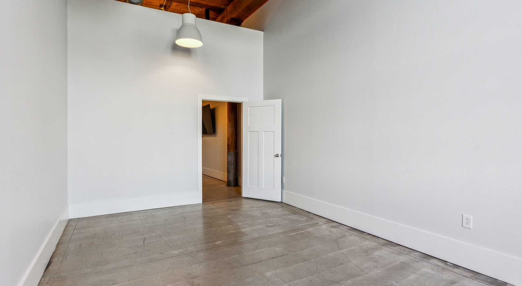 large room with door and concrete flooring