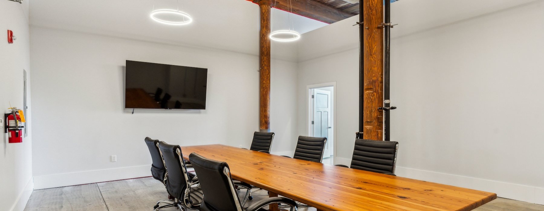 a conference room with a large table chairs and tv